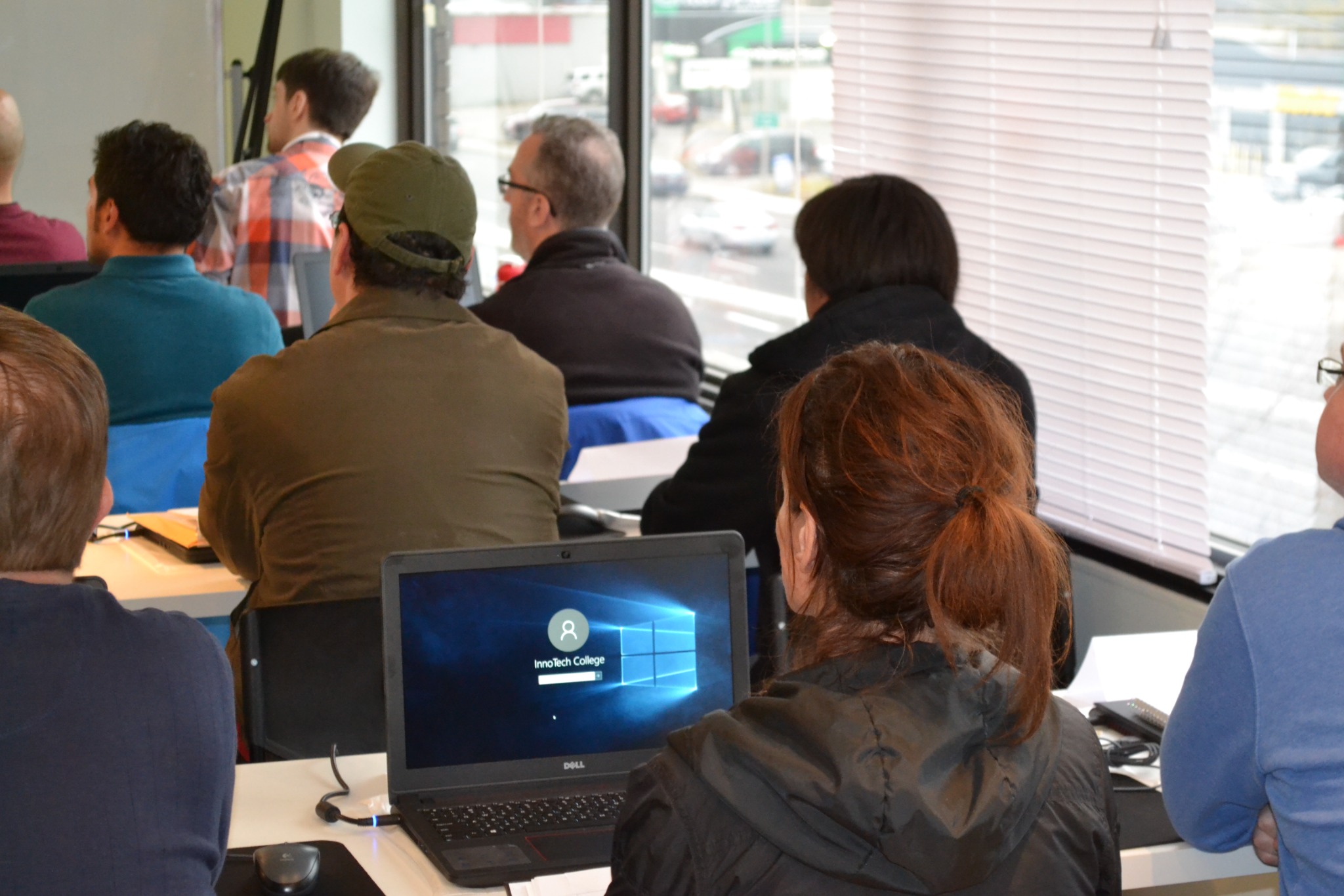 Students attending class with an InnoTech College laptop in the foreground